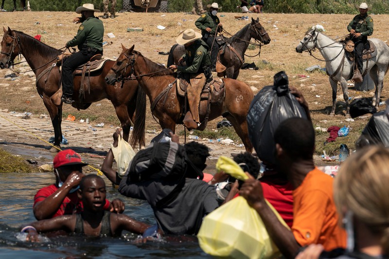 Patroli Perbatasan Amerika Serikat (AS) menggunakan kuda dalam operasi imigran ilegal Haiti U.S. Customs and Border Protection mounted officers attempt to contain migrants as they cross the Rio Grande from Ciudad Acuna, Mexico, into Del Rio, Texas, Sunday, Sept. 19, 2021. Criticism has been fueled by the images that went viral this week of Border Patrol agents on horseback using aggressive tactics against the migrants. (AP Photo/Felix Marquez)