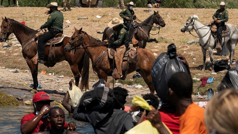 U.S. Customs and Border Protection mounted officers attempt to contain migrants as they cross the Rio Grande from Ciudad Acuna, Mexico, into Del Rio, Texas, Sunday, Sept. 19, 2021. Criticism has been fueled by the images that went viral this week of Border Patrol agents on horseback using aggressive tactics against the migrants. (AP Photo/Felix Marquez)