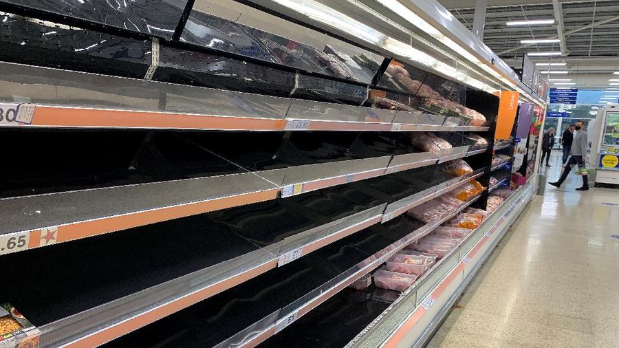 A shopper walks past empty shelves in the meat aisle of a supermarket in Manchester, Britain, September 21, 2021. REUTERS/Phil Noble