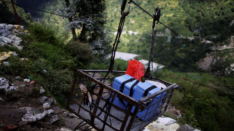 Health workers carry medical kits and a box containing COVISHIELD vaccines, before starting their trek through the mountains to vaccinate people in remote villages, as a part of a vaccination drive, during the coronavirus disease (COVID-19) outbreak, near Malana village in Kullu district in the Himalayan state of Himachal Pradesh, India, September 14, 2021. Despite the hostile terrain, the northern state of Himachal Pradesh became the first in India to administer at least one COVID-19 vaccine dose in all its adults. The steep topography was a challenge overcome by health workers walking for hours or days to reach remote villages.  REUTERS/Adnan Abidi      SEARCH 