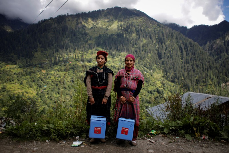 Health workers carry medical kits and a box containing COVISHIELD vaccines, before starting their trek through the mountains to vaccinate people in remote villages, as a part of a vaccination drive, during the coronavirus disease (COVID-19) outbreak, near Malana village in Kullu district in the Himalayan state of Himachal Pradesh, India, September 14, 2021. Despite the hostile terrain, the northern state of Himachal Pradesh became the first in India to administer at least one COVID-19 vaccine dose in all its adults. The steep topography was a challenge overcome by health workers walking for hours or days to reach remote villages.  REUTERS/Adnan Abidi      SEARCH 