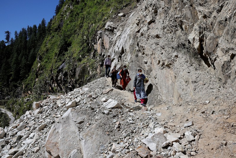 Health workers carry medical kits and a box containing COVISHIELD vaccines, before starting their trek through the mountains to vaccinate people in remote villages, as a part of a vaccination drive, during the coronavirus disease (COVID-19) outbreak, near Malana village in Kullu district in the Himalayan state of Himachal Pradesh, India, September 14, 2021. Despite the hostile terrain, the northern state of Himachal Pradesh became the first in India to administer at least one COVID-19 vaccine dose in all its adults. The steep topography was a challenge overcome by health workers walking for hours or days to reach remote villages.  REUTERS/Adnan Abidi      SEARCH 