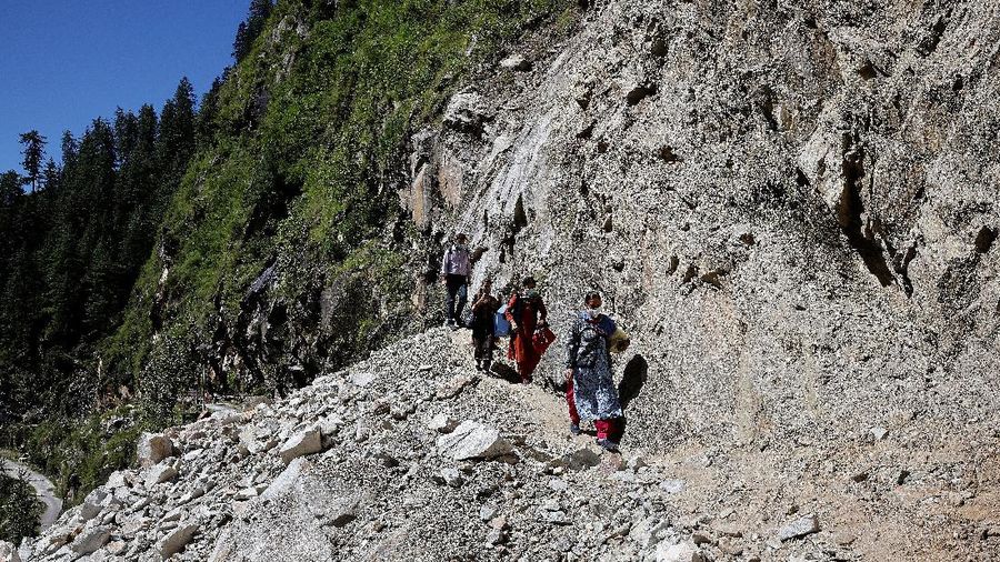 Health workers carry medical kits and a box containing COVISHIELD vaccines, before starting their trek through the mountains to vaccinate people in remote villages, as a part of a vaccination drive, during the coronavirus disease (COVID-19) outbreak, near Malana village in Kullu district in the Himalayan state of Himachal Pradesh, India, September 14, 2021. Despite the hostile terrain, the northern state of Himachal Pradesh became the first in India to administer at least one COVID-19 vaccine dose in all its adults. The steep topography was a challenge overcome by health workers walking for hours or days to reach remote villages.  REUTERS/Adnan Abidi      SEARCH 