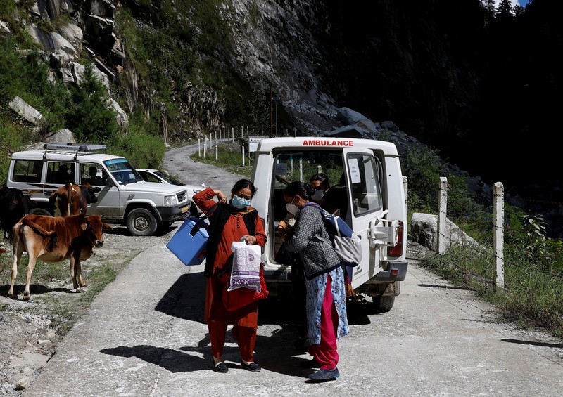Health workers carry medical kits and a box containing COVISHIELD vaccines, before starting their trek through the mountains to vaccinate people in remote villages, as a part of a vaccination drive, during the coronavirus disease (COVID-19) outbreak, near Malana village in Kullu district in the Himalayan state of Himachal Pradesh, India, September 14, 2021. Despite the hostile terrain, the northern state of Himachal Pradesh became the first in India to administer at least one COVID-19 vaccine dose in all its adults. The steep topography was a challenge overcome by health workers walking for hours or days to reach remote villages.  REUTERS/Adnan Abidi      SEARCH 