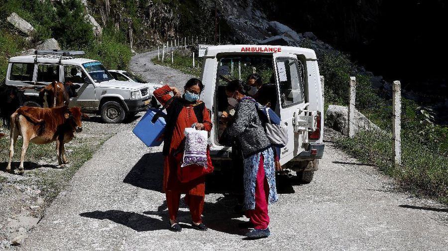 Health workers carry medical kits and a box containing COVISHIELD vaccines, before starting their trek through the mountains to vaccinate people in remote villages, as a part of a vaccination drive, during the coronavirus disease (COVID-19) outbreak, near Malana village in Kullu district in the Himalayan state of Himachal Pradesh, India, September 14, 2021. Despite the hostile terrain, the northern state of Himachal Pradesh became the first in India to administer at least one COVID-19 vaccine dose in all its adults. The steep topography was a challenge overcome by health workers walking for hours or days to reach remote villages.  REUTERS/Adnan Abidi      SEARCH 