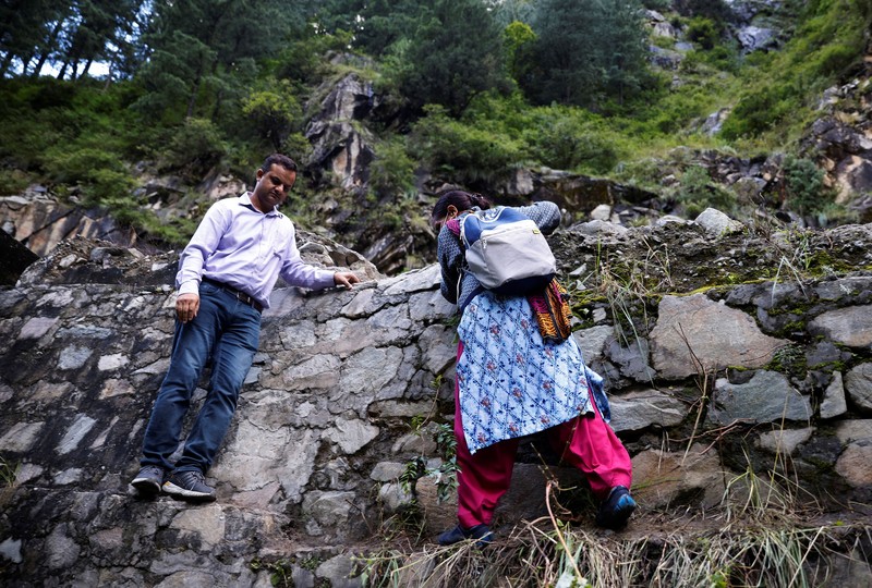 Health workers carry medical kits and a box containing COVISHIELD vaccines, before starting their trek through the mountains to vaccinate people in remote villages, as a part of a vaccination drive, during the coronavirus disease (COVID-19) outbreak, near Malana village in Kullu district in the Himalayan state of Himachal Pradesh, India, September 14, 2021. Despite the hostile terrain, the northern state of Himachal Pradesh became the first in India to administer at least one COVID-19 vaccine dose in all its adults. The steep topography was a challenge overcome by health workers walking for hours or days to reach remote villages.  REUTERS/Adnan Abidi      SEARCH 