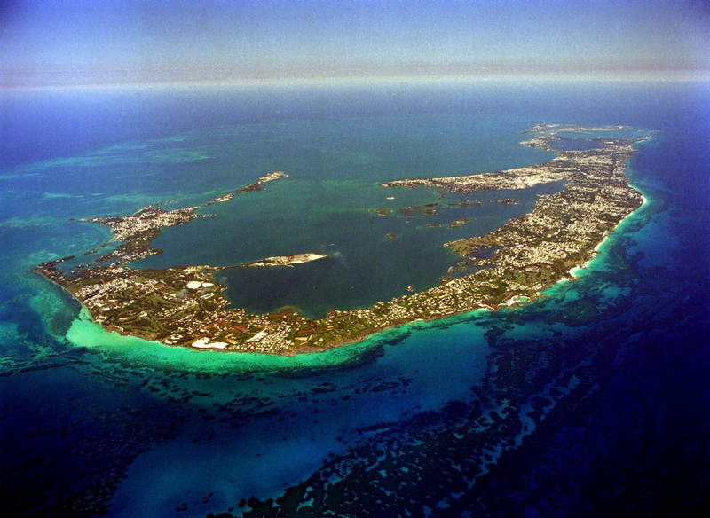 In this Aug. 3, 2012 photo, tourists walk along the beach of Seven Mile Beach in Grand Cayman Island. The Cayman Islands have lost some of their allure by abruptly proposing what amounts to an income tax on expatriate workers who have helped build the territory into one of the most famous or, for some people, notorious offshore banking centers that have tax advantages for foreign investment operations. (AP Photo/David McFadden)