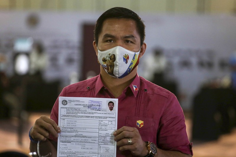 Supporters of retired Filipino boxing star and senator Manny Pacquiao gather near an area where he will file his certificate of candidacy for next year's presidential elections before the Commission on Elections on Friday, Oct. 1, 2021 in Manila, Philippines. Friday marks the start of a weeklong registration period for candidates seeking to lead a Southeast Asian nation that has been hit hard by the pandemic and deep political conflicts.(AP Photo/Aaron Favila)
