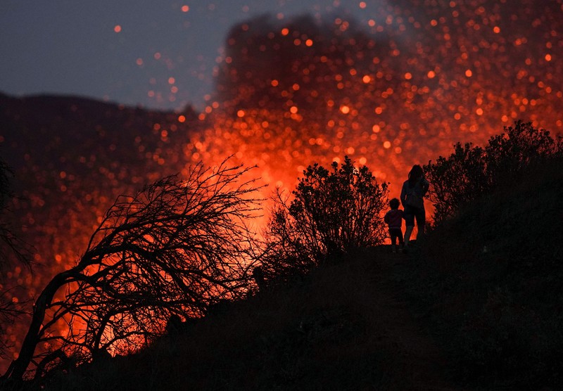 SPAIN-VOLCANO/ A woman climbs a hill with a child to see the Cumbre Vieja volcano as it continues to erupt in Tacande de Arriba on the Canary Island of La Palma, Spain, October 2, 2021. REUTERS/Juan Medina TPX IMAGES OF THE DAY