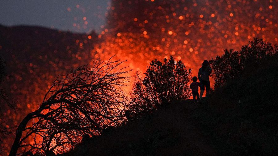 A woman climbs a hill with a child to see the Cumbre Vieja volcano as it continues to erupt in Tacande de Arriba on the Canary Island of La Palma, Spain, October 2, 2021. REUTERS/Juan Medina     TPX IMAGES OF THE DAY