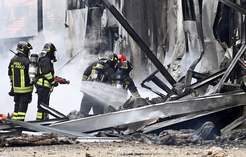 ITALY-CRASH/PLANE Fire fighters work at the scene where a small plane crashed into a building in San Donato Milanese, Italy, October 3, 2021. REUTERS/Flavio Lo Scalzo