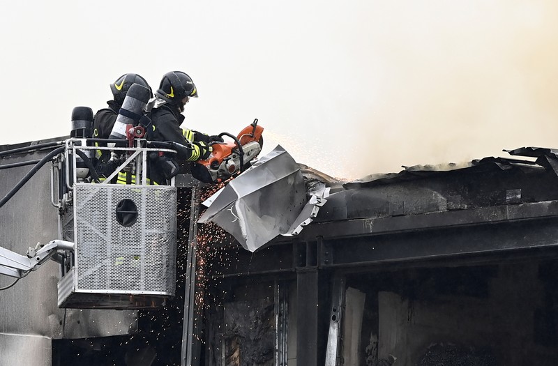 ITALY-CRASH/PLANE Fire fighters work at the scene where a small plane crashed into a building in San Donato Milanese, Italy, October 3, 2021. REUTERS/Flavio Lo Scalzo