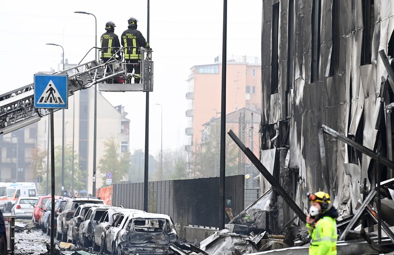 ITALY-CRASH/PLANE Fire fighters work at the scene where a small plane crashed into a building in San Donato Milanese, Italy, October 3, 2021. REUTERS/Flavio Lo Scalzo