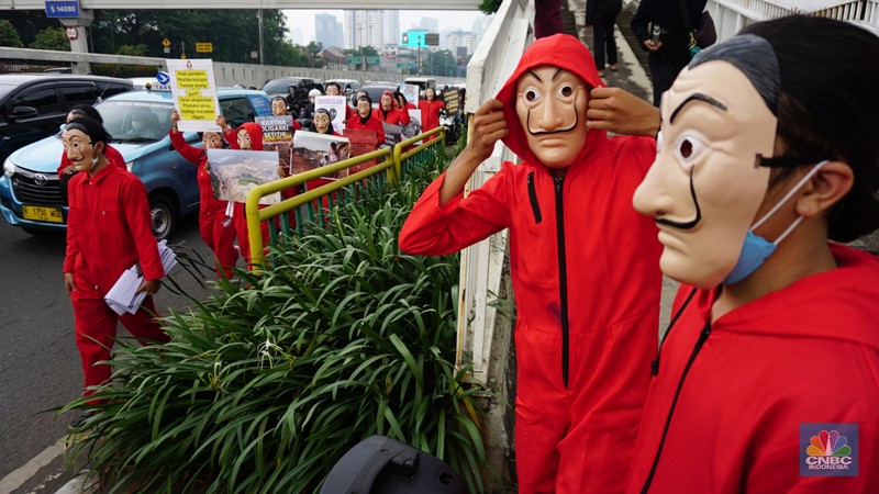 Sejumlah massa yang berkostum topeng ala money heist melakukan aksi di depan gedung DPR RI, Jakarta, Senin (4/10/2021). (CNBC Indonesia/Tri Susilo)