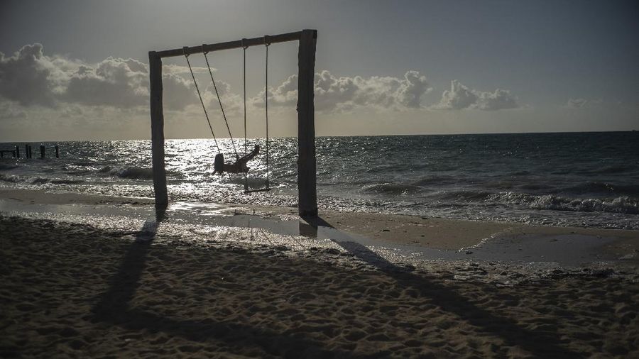 FILE - In this Aug. 30, 2019 file photo, tourist Loren Fantasia from Baltimore, swings on the beach before the arrival of Hurricane Dorian, in Freeport, Bahamas.  The Bahamas was on track for a record year of tourism before Hurricane Dorian hit. Now, the outlook for that vital sector is uncertain. Some of the best-known resorts in the 700-island chain, like Atlantis, Paradise Island, were unscathed by the monster storm.  But 100 miles away, on Grand Bahama Island and the Abaco islands, many smaller hotels and vacation rentals were damaged or destroyed. That leaves the Bahamas with a double challenge: convincing tourists to keep coming without trivializing the suffering on the affected islands. (AP Photo/Ramon Espinosa, File)