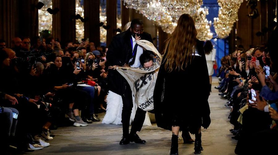 A protestor holds a banner on the runway during the Louis Vuitton Spring-Summer 2022 ready-to-wear fashion show presented in Paris, Tuesday, Oct. 5, 2021. (Photo by Vianney Le Caer/Invision/AP)