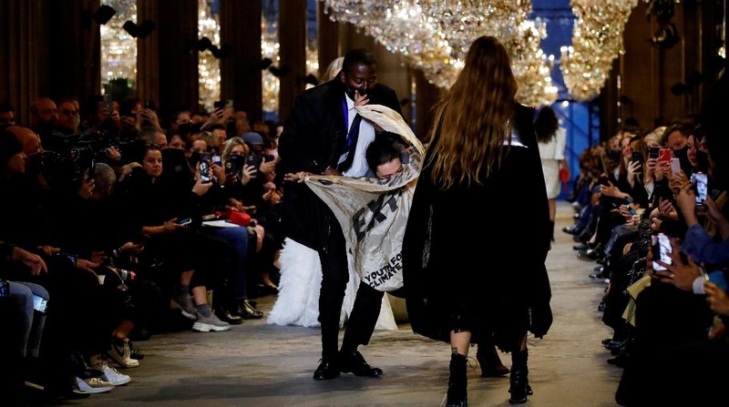 A protestor holds a banner on the runway during the Louis Vuitton Spring-Summer 2022 ready-to-wear fashion show presented in Paris, Tuesday, Oct. 5, 2021. (Photo by Vianney Le Caer/Invision/AP)