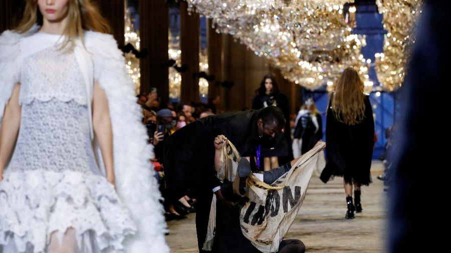 A protestor holds a banner on the runway during the Louis Vuitton Spring-Summer 2022 ready-to-wear fashion show presented in Paris, Tuesday, Oct. 5, 2021. (Photo by Vianney Le Caer/Invision/AP)