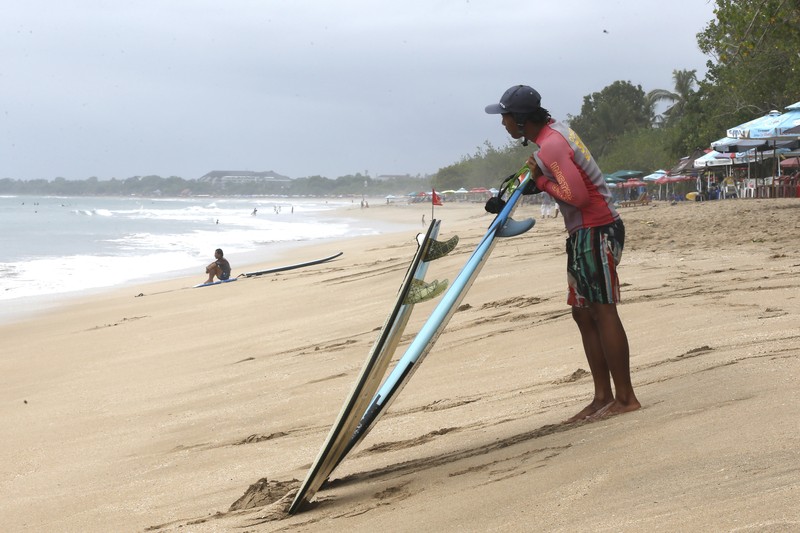 Virus Outbreak Indonesia A surf instructor prepares for surf lesson to a tourist at Kuta beach, Bali, Indonesia on Wednesday, Oct. 6, 2021. Indonesia plans to reopen the airport in the resort island of Bali for international flights on Oct. 14, after closing it for more than a year because of the COVID-19 pandemic. (AP Photo/Firdia Lisnawati)