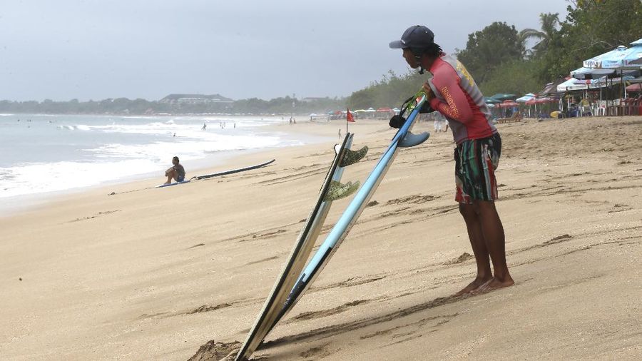 A surf instructor prepares for surf lesson to a tourist at Kuta beach, Bali, Indonesia on Wednesday, Oct. 6, 2021. Indonesia plans to reopen the airport in the resort island of Bali for international flights on Oct. 14, after closing it for more than a year because of the COVID-19 pandemic. (AP Photo/Firdia Lisnawati)