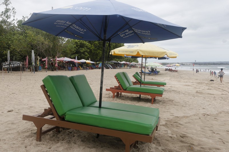 A surf instructor prepares for surf lesson to a tourist at Kuta beach, Bali, Indonesia on Wednesday, Oct. 6, 2021. Indonesia plans to reopen the airport in the resort island of Bali for international flights on Oct. 14, after closing it for more than a year because of the COVID-19 pandemic. (AP Photo/Firdia Lisnawati)
