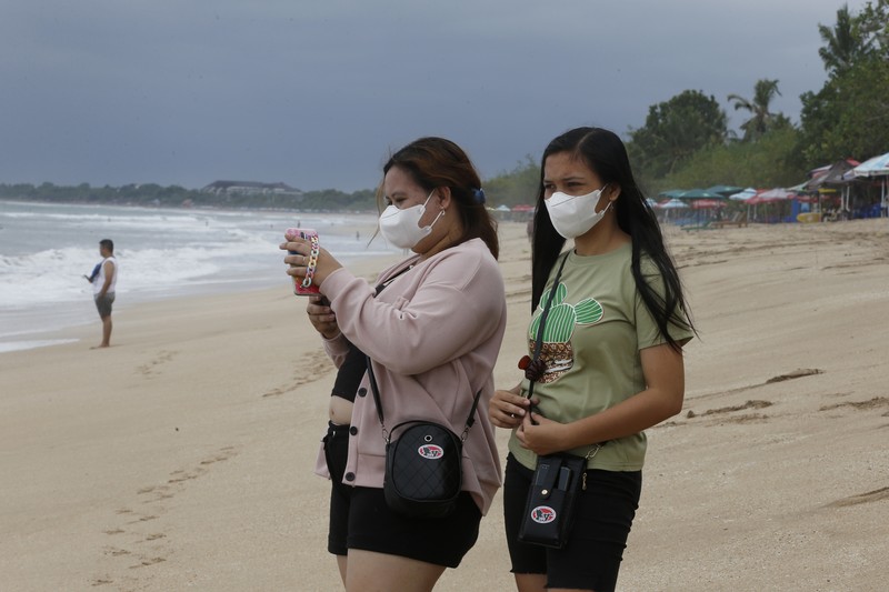 Virus Outbreak Indonesia A surf instructor prepares for surf lesson to a tourist at Kuta beach, Bali, Indonesia on Wednesday, Oct. 6, 2021. Indonesia plans to reopen the airport in the resort island of Bali for international flights on Oct. 14, after closing it for more than a year because of the COVID-19 pandemic. (AP Photo/Firdia Lisnawati)