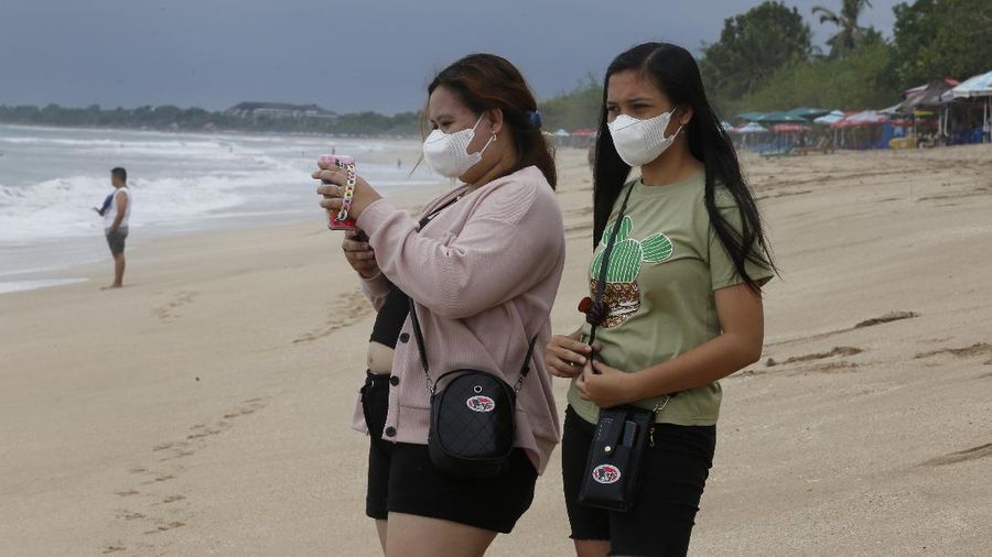 A surf instructor prepares for surf lesson to a tourist at Kuta beach, Bali, Indonesia on Wednesday, Oct. 6, 2021. Indonesia plans to reopen the airport in the resort island of Bali for international flights on Oct. 14, after closing it for more than a year because of the COVID-19 pandemic. (AP Photo/Firdia Lisnawati)