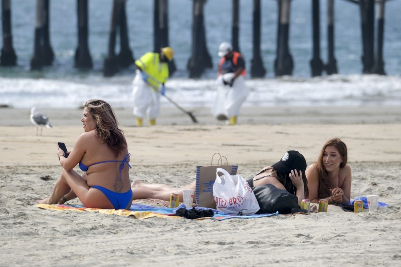 California Oil Spill People play on the sand in the background as workers in protective suits clean the contaminated beach after an oil spill in Newport Beach, Calif., on Wednesday, Oct. 6, 2021. A major oil spill off the coast of Southern California fouled popular beaches and killed wildlife while crews scrambled Sunday, to contain the crude before it spread further into protected wetlands. (AP Photo/Ringo H.W. Chiu)