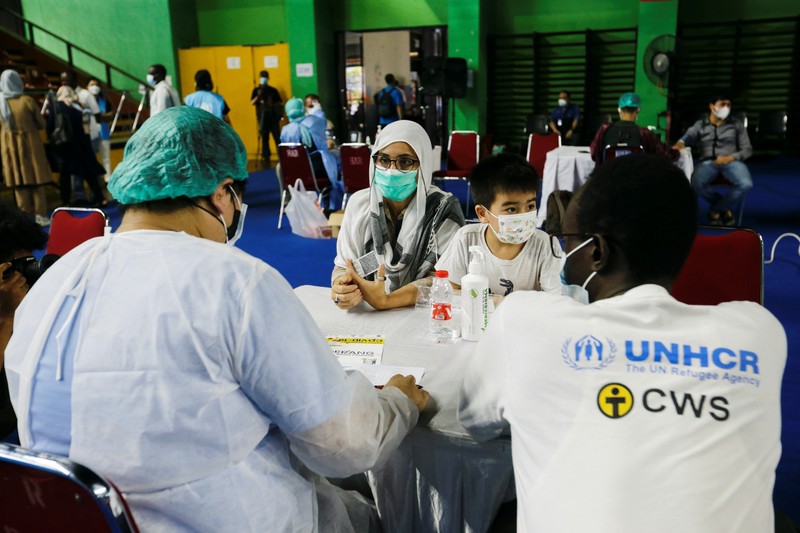 A woman undergoes a health screening before receiving a dose of a vaccine against the coronavirus disease (COVID-19) during a mass vaccination program for asylum seekers and refugees at a sports hall in Jakarta, Indonesia, October 7, 2021. REUTERS/Ajeng Dinar Ulfiana