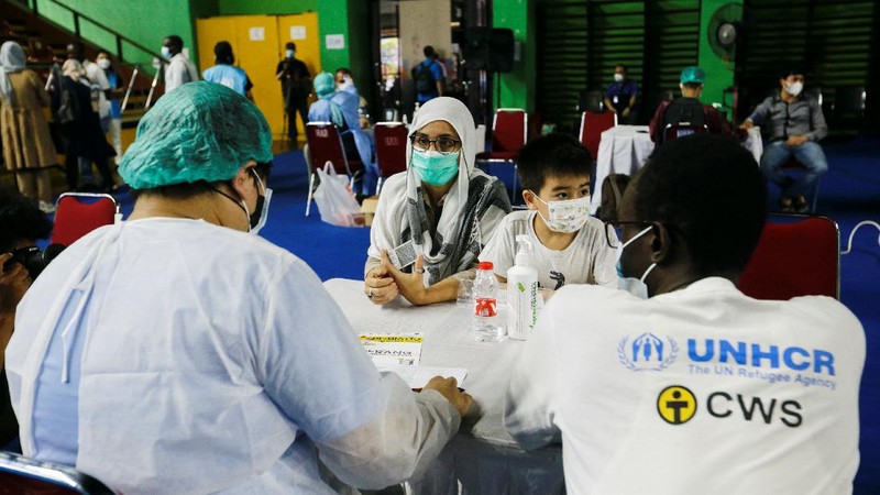 A woman undergoes a health screening before receiving a dose of a vaccine against the coronavirus disease (COVID-19) during a mass vaccination program for asylum seekers and refugees at a sports hall in Jakarta, Indonesia, October 7, 2021. REUTERS/Ajeng Dinar Ulfiana