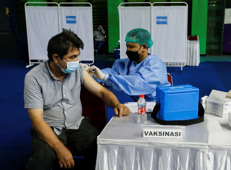 A woman undergoes a health screening before receiving a dose of a vaccine against the coronavirus disease (COVID-19) during a mass vaccination program for asylum seekers and refugees at a sports hall in Jakarta, Indonesia, October 7, 2021. REUTERS/Ajeng Dinar Ulfiana