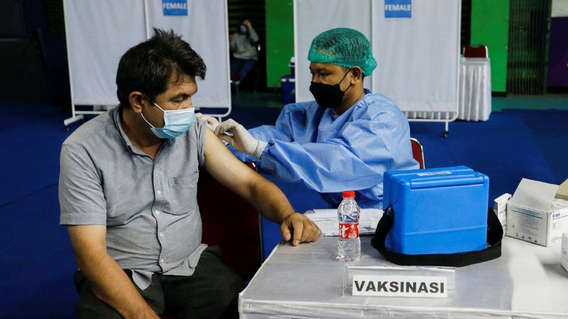 A woman undergoes a health screening before receiving a dose of a vaccine against the coronavirus disease (COVID-19) during a mass vaccination program for asylum seekers and refugees at a sports hall in Jakarta, Indonesia, October 7, 2021. REUTERS/Ajeng Dinar Ulfiana