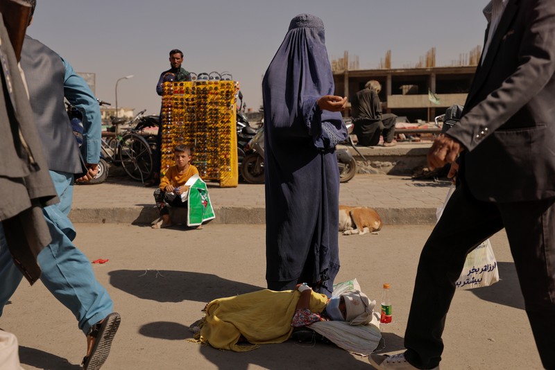 Seorang wanita Afghanistan mengenakan burqa memohon saat merawat putrinya di Kabul, Afghanistan 7 Oktober 2021. (REUTERS/Jorge Silva) An Afghan woman wearing a burqa begs while taking care of her daughter in Kabul, Afghanistan October 7, 2021. Picture taken October 7, 2021. REUTERS/Jorge Silva