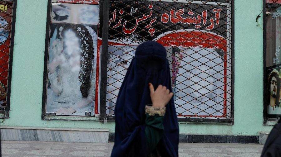 An Afghan woman wearing a burqa begs while taking care of her daughter in Kabul, Afghanistan October 7, 2021. Picture taken October 7, 2021. REUTERS/Jorge Silva