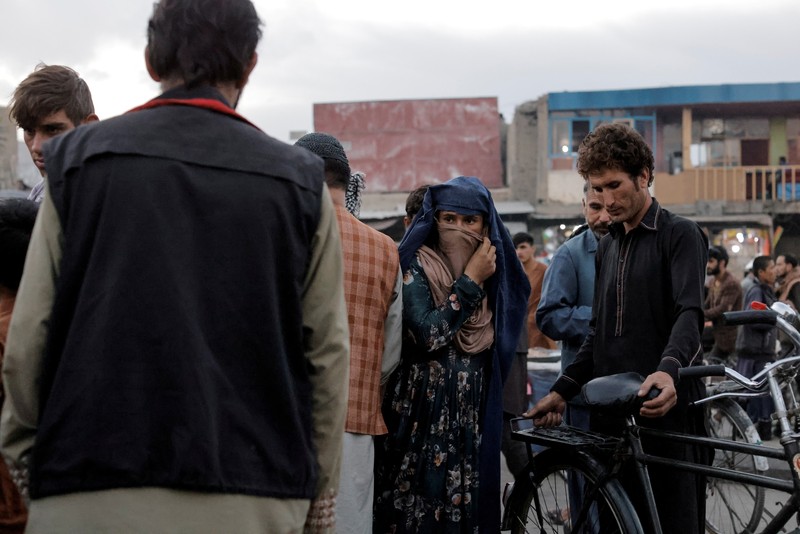 An Afghan woman wearing a burqa begs while taking care of her daughter in Kabul, Afghanistan October 7, 2021. Picture taken October 7, 2021. REUTERS/Jorge Silva