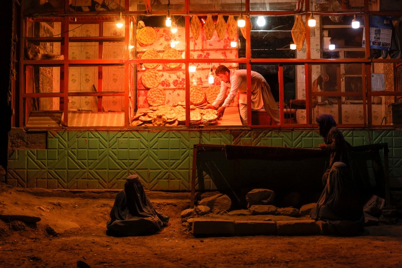 An Afghan woman wearing a burqa begs while taking care of her daughter in Kabul, Afghanistan October 7, 2021. Picture taken October 7, 2021. REUTERS/Jorge Silva