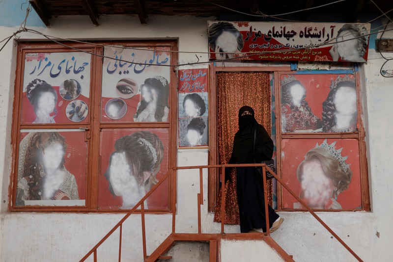 An Afghan woman wearing a burqa begs while taking care of her daughter in Kabul, Afghanistan October 7, 2021. Picture taken October 7, 2021. REUTERS/Jorge Silva
