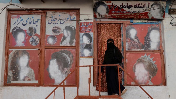 A woman wearing a niqab enters a beauty salon where the ads of women have been defaced by a shopkeeper in Kabul, Afghanistan October 6, 2021. REUTERS/Jorge Silva     TPX IMAGES OF THE DAY