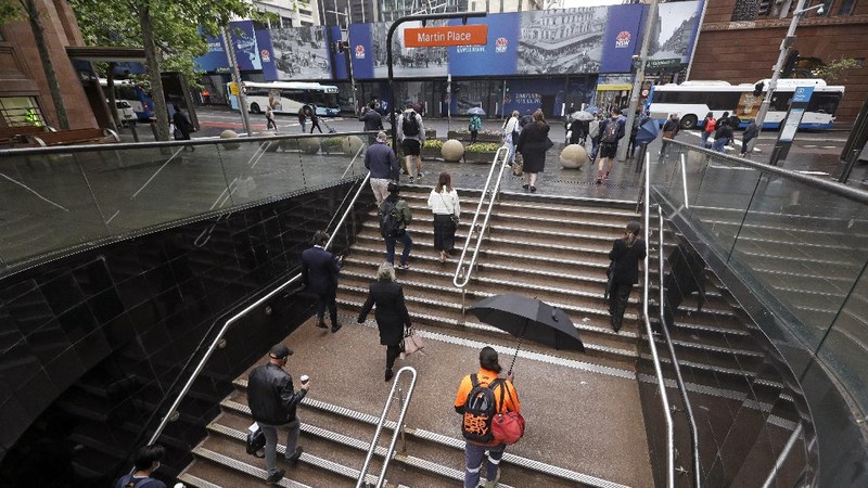 Commuters walk out of an underground train station as people filter into the city after more than 100 days of lockdown to help contain the COVID-19 outbreak in Sydney, Monday, Oct. 11, 2021. (AP Photo/Rick Rycroft)