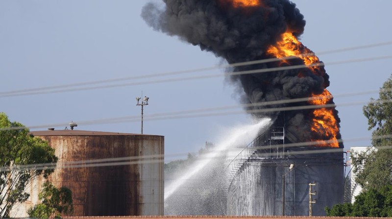 Firefighters work to extinguish a fire at an oil facility in the southern town of Zahrani, south of the port city of Sidon, Lebanon, Monday, Oct. 11, 2021. The cause of the huge fire was not immediately known. (AP Photo/Hassan Ammar)