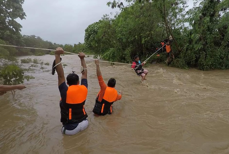 In this photo released by the Gonzaga Municipal Disaster Risk Reduction and Management Office, a resident is pulled along a rope as rescuers wait on the other side of a swollen river caused by heavy rains from Tropical Storm Kompasu in Gonzaga town, Cagayan province, northern Philippines, Monday Oct. 11, 2021. A number of people have been killed and others were reported missing in landslides and flash flood set off by a storm that barreled through the tip of the northern Philippines overnight then blew away Tuesday, officials said. (Gonzaga MDRRMO via AP)