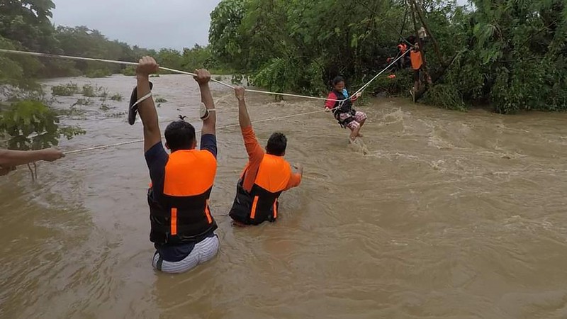 In this photo released by the Gonzaga Municipal Disaster Risk Reduction and Management Office, a resident is pulled along a rope as rescuers wait on the other side of a swollen river caused by heavy rains from Tropical Storm Kompasu in Gonzaga town, Cagayan province, northern Philippines, Monday Oct. 11, 2021. A number of people have been killed and others were reported missing in landslides and flash flood set off by a storm that barreled through the tip of the northern Philippines overnight then blew away Tuesday, officials said. (Gonzaga MDRRMO via AP)