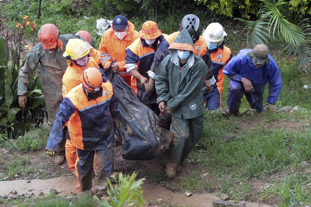 Rescuers carry the body of a victim caught in a landslide caused by Tropical Storm Kompasu in Baguio city, northern Philippines on Tuesday Oct. 12, 2021. A number of people have been killed and others were reported missing in landslides and flash flood set off by a storm that barreled through the tip of the northern Philippines overnight then blew away Tuesday, officials said. (AP Photo)