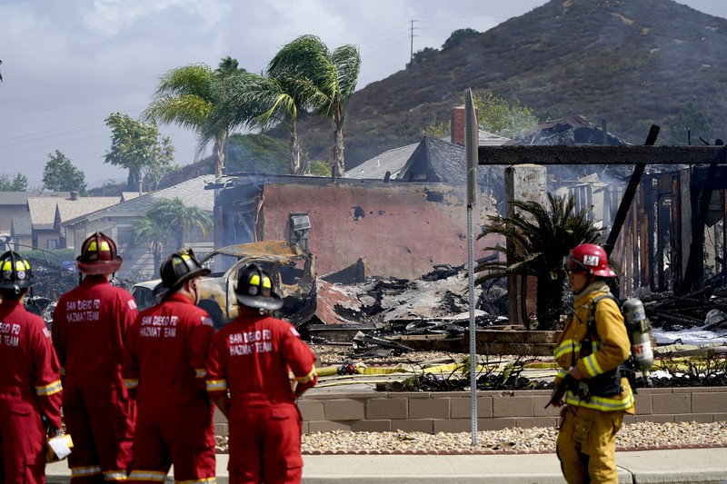 kecelakaan pesawat di Santee, California, AS Fire crews work the scene of a small plane crash, Monday, Oct. 11, 2021, in Santee, Calif. At least two people were killed and two others were injured when the plane crashed into a suburban Southern California neighborhood, setting two homes ablaze, authorities said. (AP Photo/Gregory Bull)