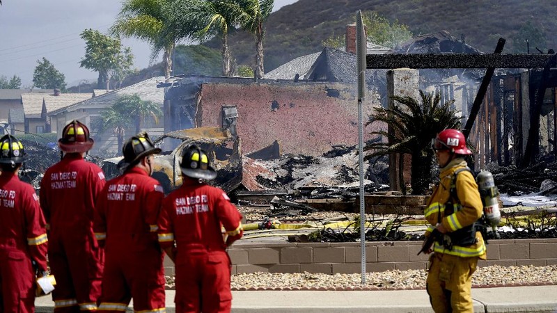 Fire crews work the scene of a small plane crash, Monday, Oct. 11, 2021, in Santee, Calif. At least two people were killed and two others were injured when the plane crashed into a suburban Southern California neighborhood, setting two homes ablaze, authorities said. (AP Photo/Gregory Bull)