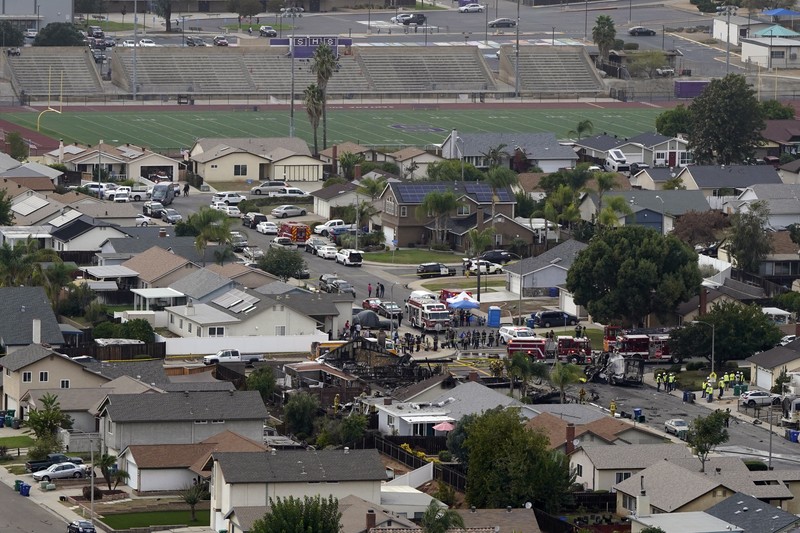 kecelakaan pesawat di Santee, California, AS Fire crews work the scene of a small plane crash, Monday, Oct. 11, 2021, in Santee, Calif. At least two people were killed and two others were injured when the plane crashed into a suburban Southern California neighborhood, setting two homes ablaze, authorities said. (AP Photo/Gregory Bull)