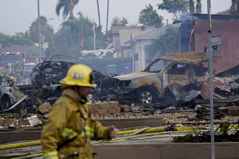 kecelakaan pesawat di Santee, California, AS Fire crews work the scene of a small plane crash, Monday, Oct. 11, 2021, in Santee, Calif. At least two people were killed and two others were injured when the plane crashed into a suburban Southern California neighborhood, setting two homes ablaze, authorities said. (AP Photo/Gregory Bull)