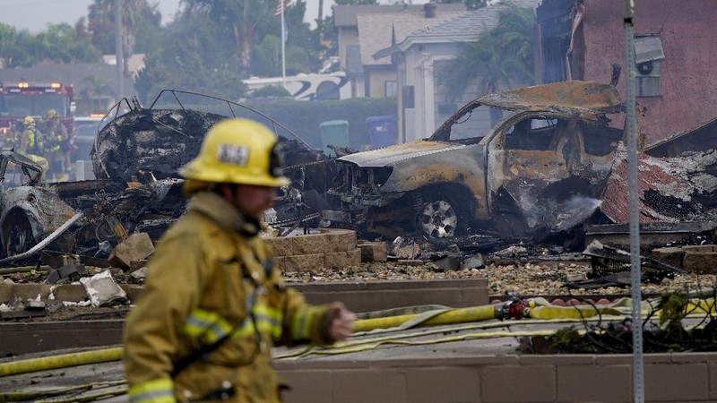 Fire crews work the scene of a small plane crash, Monday, Oct. 11, 2021, in Santee, Calif. At least two people were killed and two others were injured when the plane crashed into a suburban Southern California neighborhood, setting two homes ablaze, authorities said. (AP Photo/Gregory Bull)