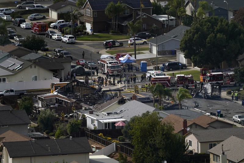 kecelakaan pesawat di Santee, California, AS Fire crews work the scene of a small plane crash, Monday, Oct. 11, 2021, in Santee, Calif. At least two people were killed and two others were injured when the plane crashed into a suburban Southern California neighborhood, setting two homes ablaze, authorities said. (AP Photo/Gregory Bull)