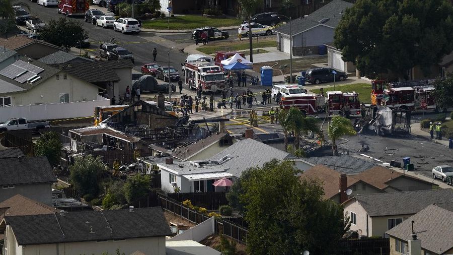 Fire crews work the scene of a small plane crash, Monday, Oct. 11, 2021, in Santee, Calif. At least two people were killed and two others were injured when the plane crashed into a suburban Southern California neighborhood, setting two homes ablaze, authorities said. (AP Photo/Gregory Bull)